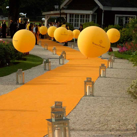 orange helium balloon lined carpet walkway leading up to party entrance
