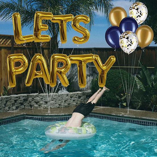 Let's Party spelled out with giant gold letter balloons next to a pool
