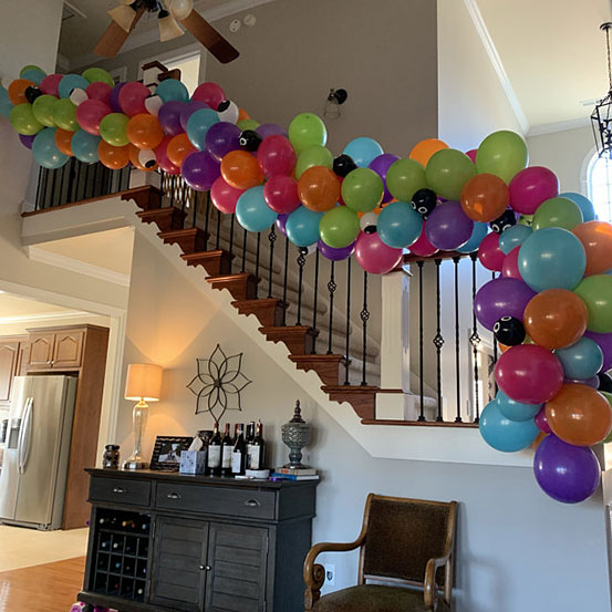 balloon garland hung on staircase handrail in a house