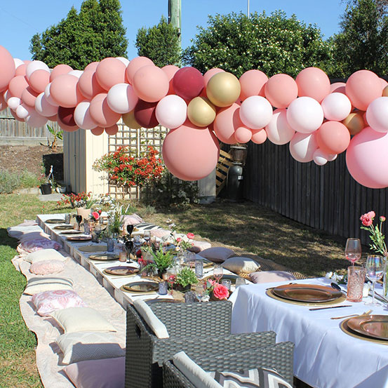balloon garland hung above a party dining area in back yard
