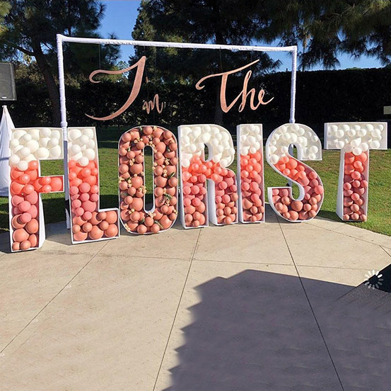 I'm the Florist spelled out with white and pink balloon mosaic letters in a yard