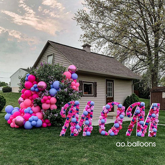 Mom spelled out with pink and purple balloon mosaic letters outside a house