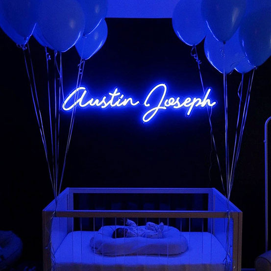 Austin Joseph custom name blue neon sign above baby's crib with balloons