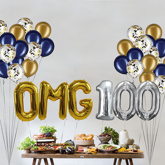 Giant gold and silver letter balloons spelling the phrase OMG 100 above a buffet table