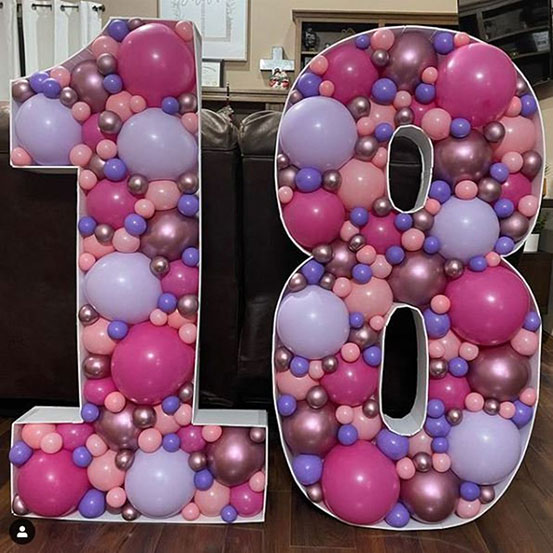 18 balloon mosaic numbers filled with black balloons inside a house