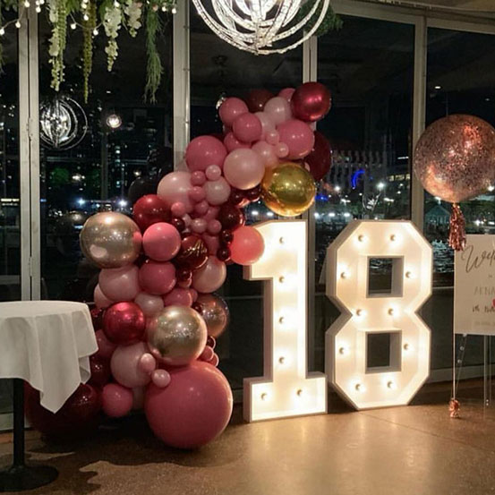 Large marquee letters spelling 18 surrounded by balloons