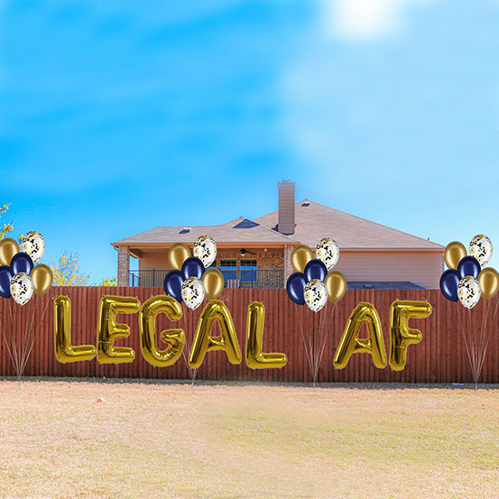 Bring It On spelled out with giant gold letter balloons along a fence in a yard