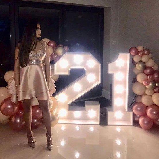 Large marquee letters spelling 21 surrounded by balloons