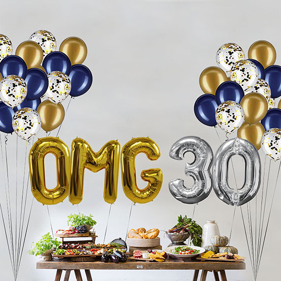 Giant gold and silver letter balloons spelling the phrase OMG 30 above a buffet table