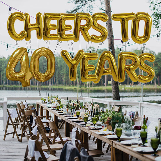 Cheers to 40 Years spelled out with giant gold letter balloons above birthday dining tables