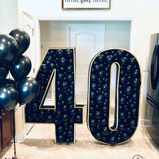 40 balloon mosaic numbers filled with black balloons inside a house