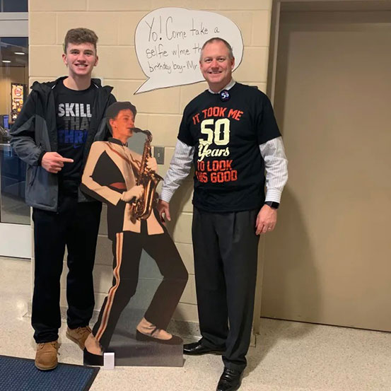 man standing next to a life size cutout of himself at a 50th birthday party