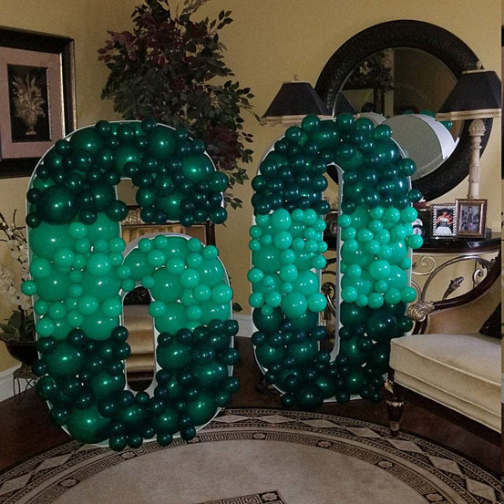 60 balloon mosaic numbers filled with black balloons inside a house