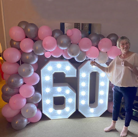 Large marquee letters spelling 60 surrounded by balloons