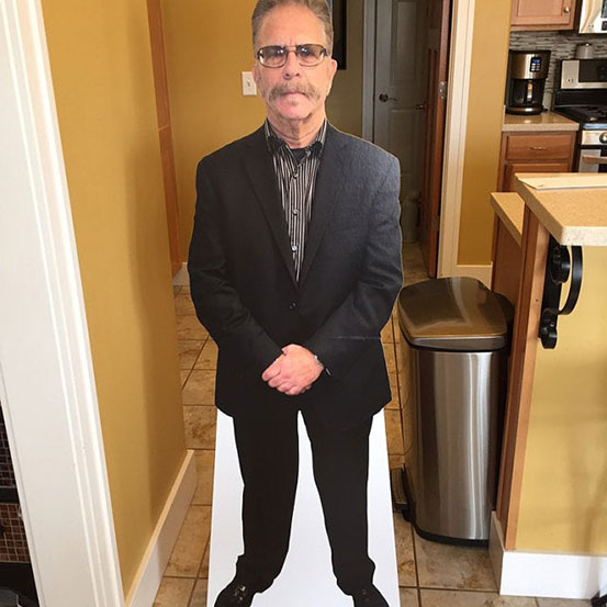 man standing next to a life size cutout of himself at a 65th birthday party