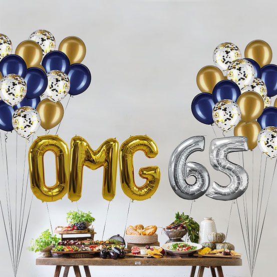 Giant gold and silver letter balloons spelling the phrase OMG 65 above a buffet table