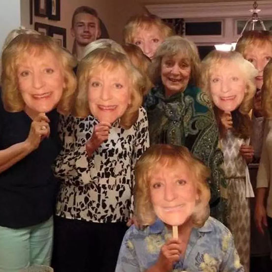 Group of people at a party holding up fan faces of the birthday boy's face