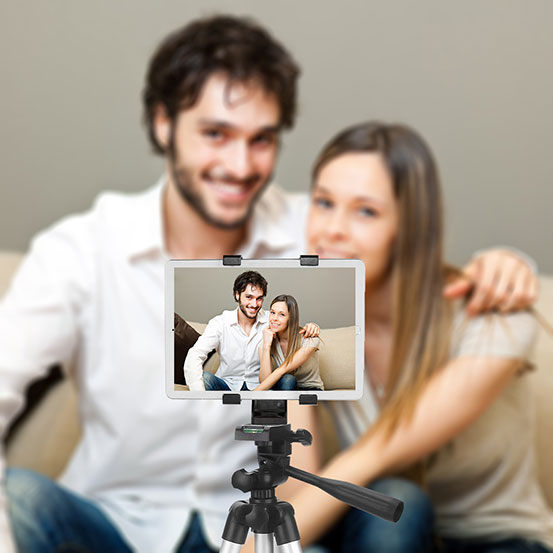 man and woman raising their glasses to toast while recording a video message on a tablet on a tripod