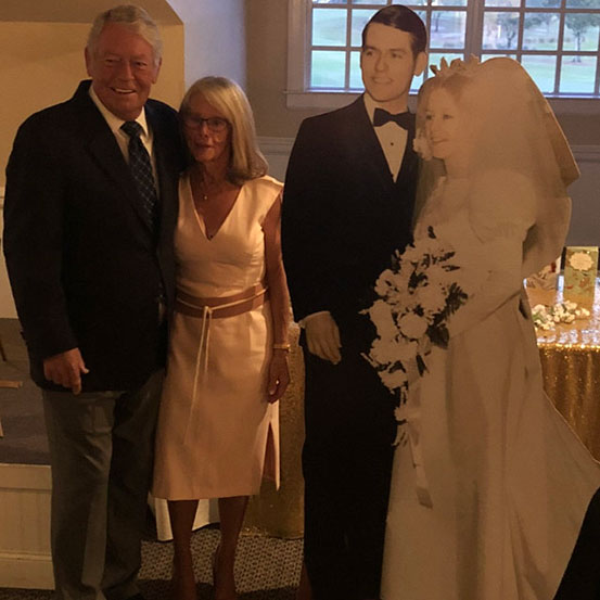 man standing next to a life size cutout of himself at a 80th birthday party