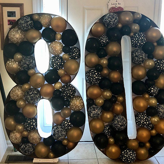 80 balloon mosaic numbers filled with black balloons inside a house