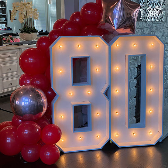 Large marquee letters spelling 30 surrounded by balloons