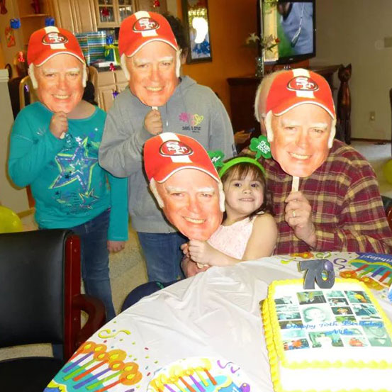 Group of people at a party holding up fan faces of the birthday girl's face