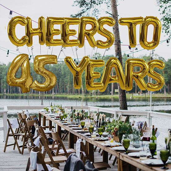 Cheers to 30 years spelled out with giant gold letter balloons above birthday dining tables