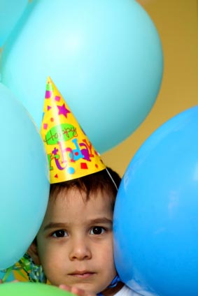 toddler boy with party hat and balloons