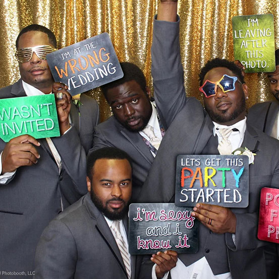 group of men holding up photo booth props and signs at a wedding party