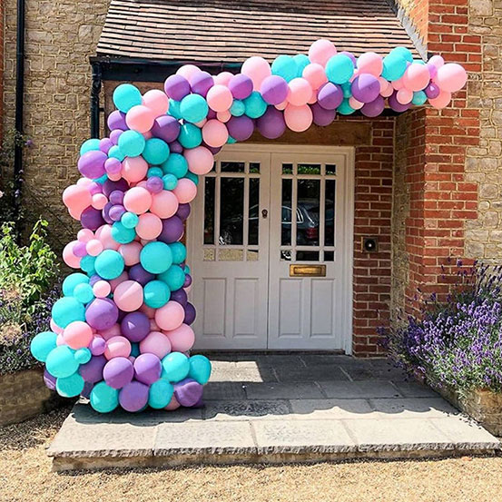 Purple, blue and pink balloon garland surrounding the entrance to a house
