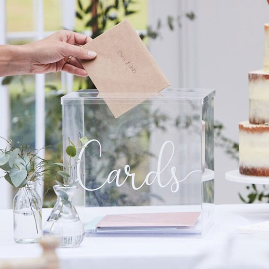 acrylic card box on a table at wedding with someone putting a card inside