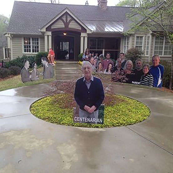 Half body cut outs of the birthday boy and friends and family arranged as lawn signs leading up to house