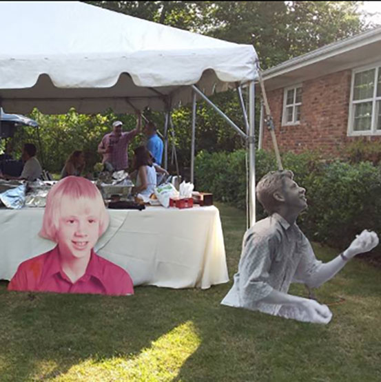Half body cut outs of the birthday boy at different ages set up at a garden party