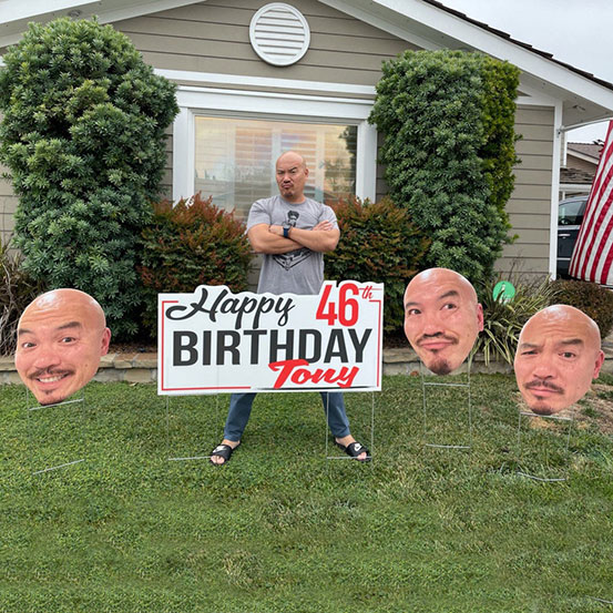 Happy 46th Birthday Tony yard sign surrounded by photo heads of man arranged as lawn signs outside a house