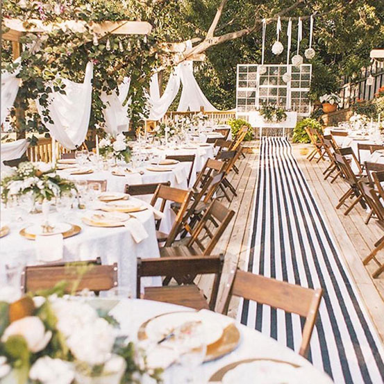 black and white striped fabric aisle runner at outdoor wedding reception surrounded by dinner tables