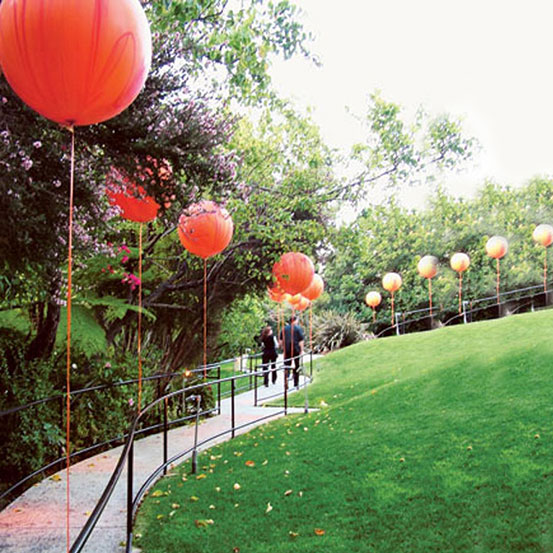 red helium balloon lined walkway through a park