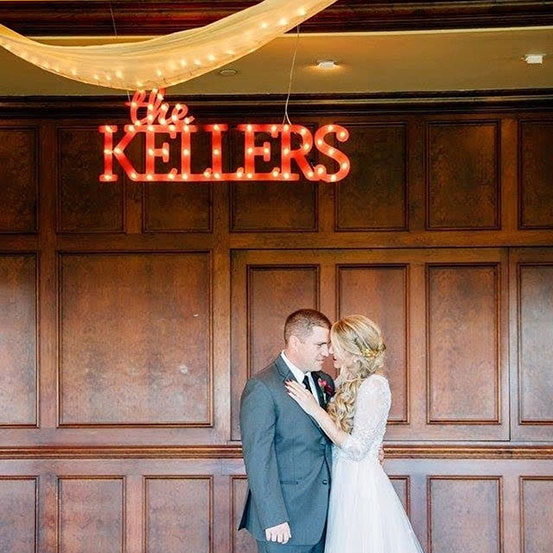 small marquee letters spelling The Kellers hung from ceiling above bride and groom at wedding