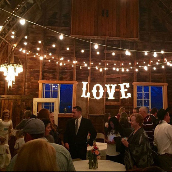 small marquee letters spelling LOVE hung from ceiling in a barn at a wedding