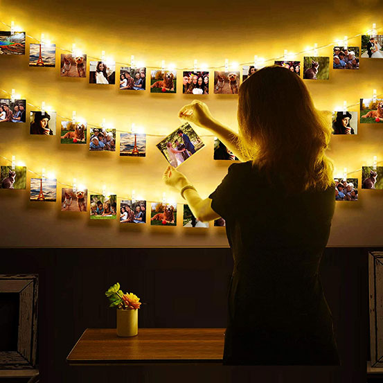 woman hanging photos to LED photo clip string lights