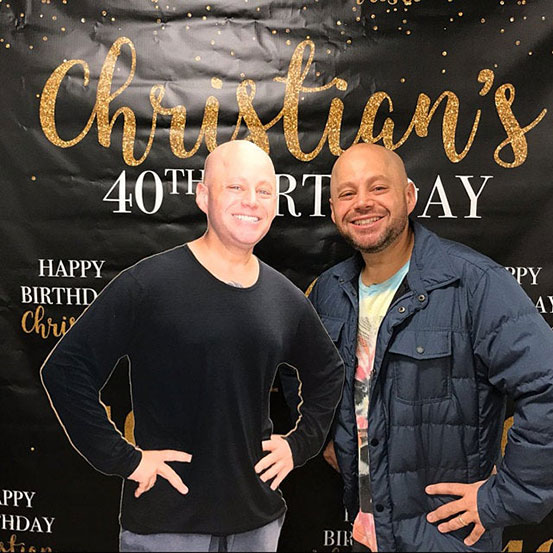 man standing next to a life size cutout of himself at a 40th birthday party
