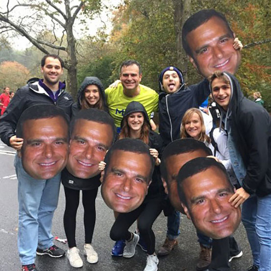 group of people holding big head cut outs of a man's face