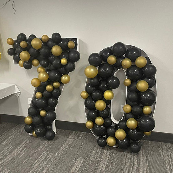 70 balloon mosaic numbers filled with black balloons inside a house