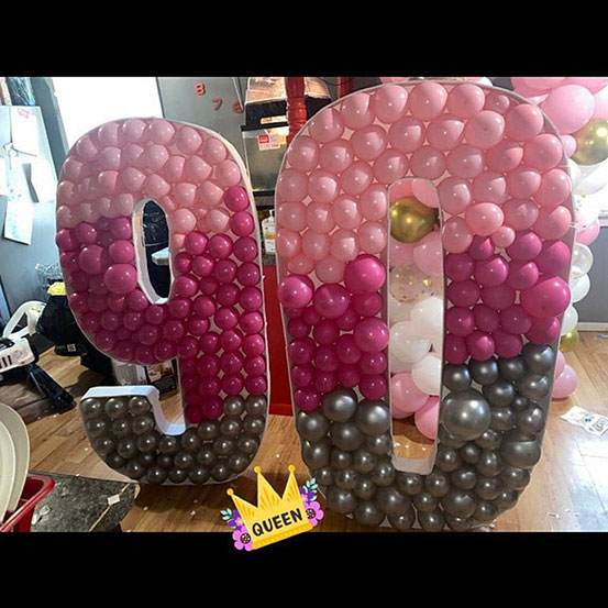 95 balloon mosaic numbers filled with black balloons inside a house