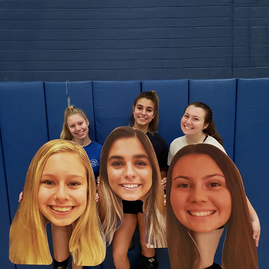group of people holding big head cut outs of a man's face