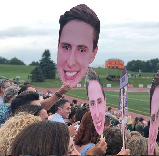 group of young people holding big head cutouts