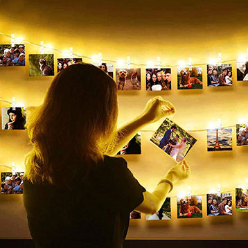 woman hanging a photo on photo garland banners with LED light clips