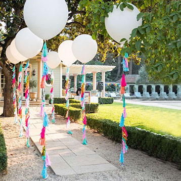 white helium balloons line entrance to party
